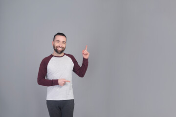 Young man standing pointing at copy space in a studio shot - 565303053