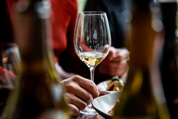 man hand hold glass of white wine on the table