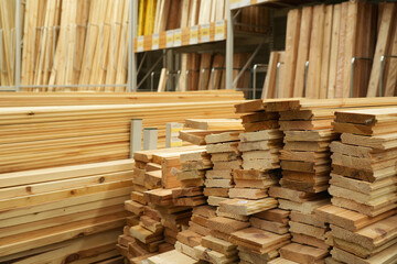 Obraz premium Pile of wood on store shelves. Wooden boards, lining, boards for construction work are presented in the hardware store. Building and finishing materials store