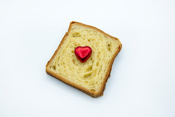 Una tostada de pan de molde con un corazón de chocolate rojo sobre fondo blanco. 