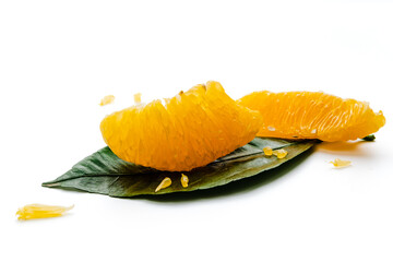 Peeled orange fruit pulp on green leaf isolated on white background. Macro photo of citrus fruit slice. Fresh, juicy pulp of orange