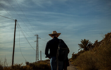 Rear view of adult man walking on dirt road