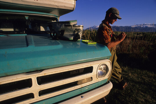 A man ties a fly next to his truck while fly fishing in Bishop, California.