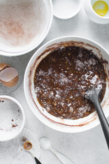 Loosely folded chocolate cake batter in a white bowl, chocolate madeleines batter being mixed