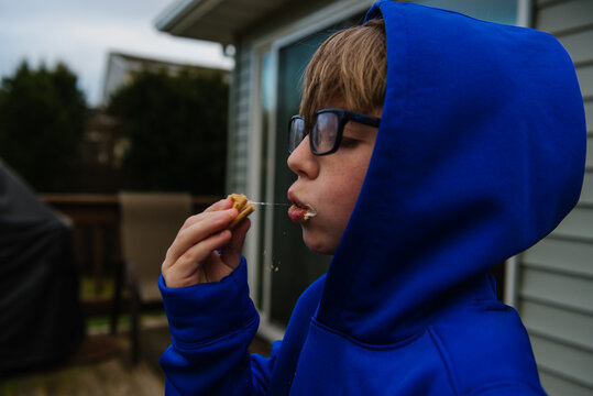 Boy eating S'more with marshmallow and glasses