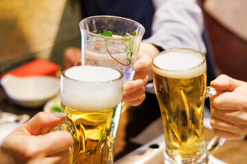 飲食店でビールとサワーで乾杯する人たち