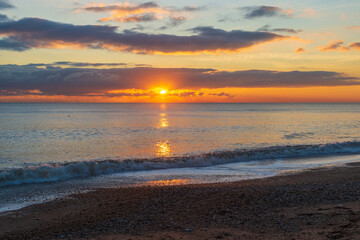 Fototapeta na wymiar The sunsetting over the English Channel viewed from Brighton Beach, UK