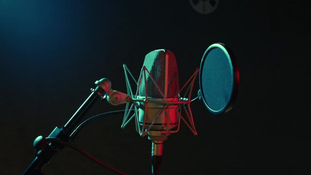 Professional microphone is in dark recording hall. Sound department with musical equipment. Audio studio for radio broadcast, production of hit songs, phonogram, singer albums. Close up