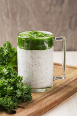 Chia seed pudding with curly kale in glass on light wooden background. Healthy breakfast. Clean eating and superfoods concept. Vertical orientation.