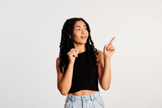 A surprised young woman pointing and looking at copy space in a studio shot