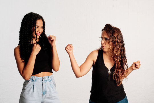 Two women facing each other in a fight pose in a studio shot