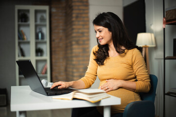 Beautiful pregnant woman working on laptop. Young businesswoman working in her office.