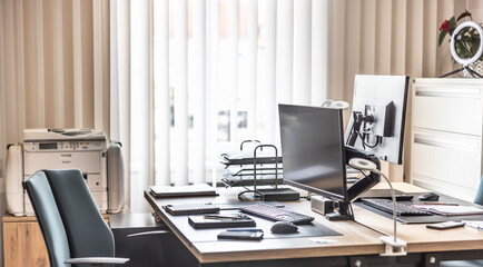 Empty office equipped with computers, tablets, printer and office furniture