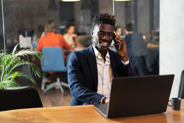 Portrait of successful businessman in office. Young smiling man talking to the phone.