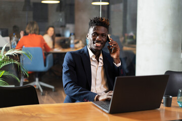 Obraz premium Portrait of successful businessman in office. Young smiling man talking to the phone.