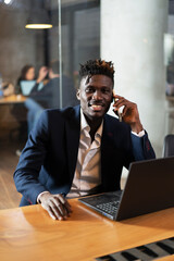 Portrait of successful businessman in office. Young smiling man talking to the phone.