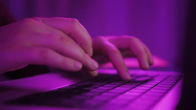 Freelancer working on laptop at home office. Close up of hands typing on laptop.