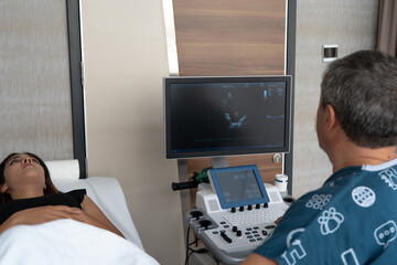 Doctor looking at ultrasound images, Doctor examining ultrasound of female patient and talking to woman about her illness