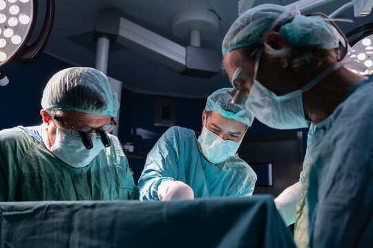 Open heart surgery, doctors and cardiologists perform open heart surgery. Doctors in green uniforms in the operating room.