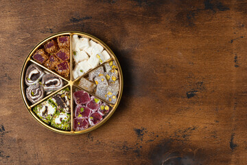 Assorti of traditional turkish delights lokum in a round gift golden box. Wooden background. Top view, copy space