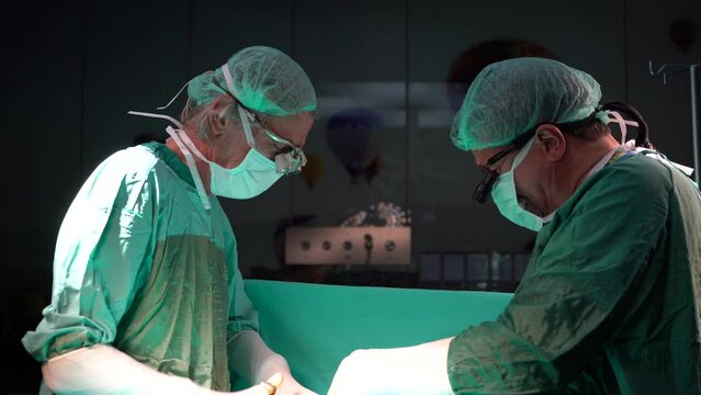 Open heart surgery, doctors and cardiologists perform open heart surgery. Doctors in green uniforms in the operating room.