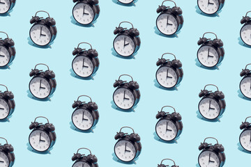 Seamless pattern of black retro alarm clocks  show 3 o'clock and one shows 2. Changing clock from...