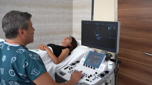 Doctor looking at ultrasound images, Doctor examining ultrasound of female patient and talking to woman about her illness