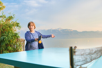 Kid boy playing  ping pong by the lake, active lifestyle for children