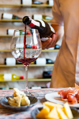 Waiter pouring red wine in glasses for wine on the table in restaurant