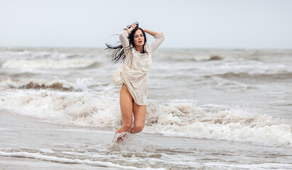 Fototapeta na wymiar Seminude woman in the cold sea waves