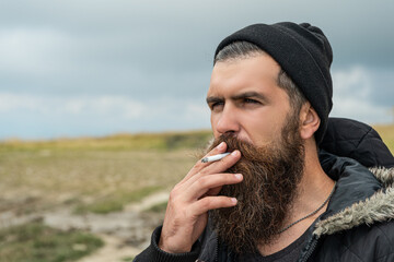 man with beard smoking cigarette, advertisement. bearded man smoking cigarette.