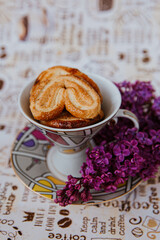 a cup with cookies stands next to a purple lilac 
