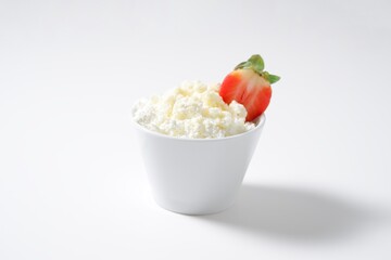 Cottage cheese with strawberries in a white bowl on a white background