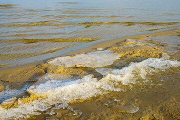 sandy shore with ice and water. View of the winter beach