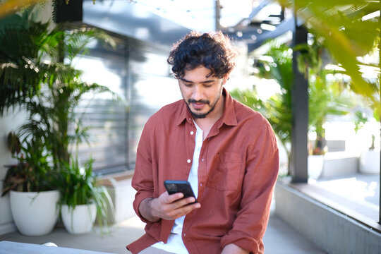 Man smiling on mobile phone in open room with plants