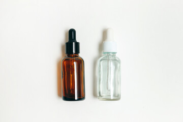 Two cosmetics glass dropper bottles for essential oil or serum on white background. Flat lay