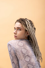 Queer person with dreadlocks looking at camera isolated on yellow.