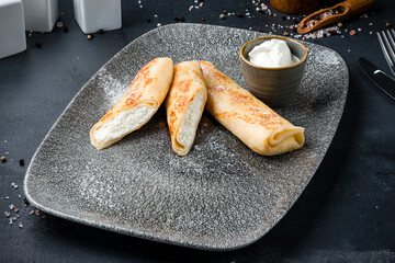 Breakfast sweet thin pancakes with cottage cheese and sour cream.