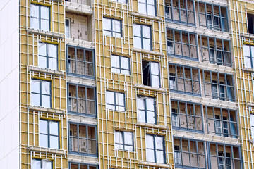Insulation of residential building, external facade works. Cladding of building, facade insulation, building facing work. Facade wall with frame for facade cladding panels. Thermal wool insulation