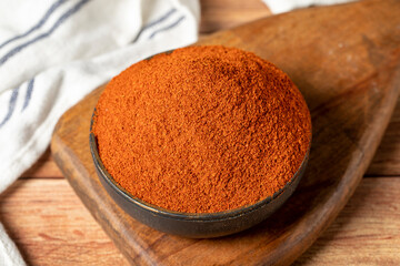 Red chili powder spice. Ground sweet paprika spice in bowl on wood background. Dry spice concept. close up