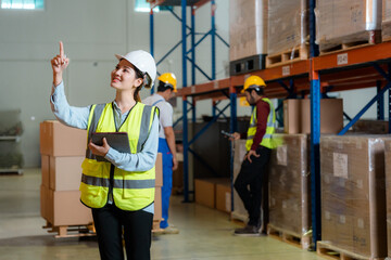 Asian employees work together to check goods in a large warehouse.