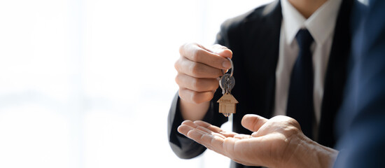 home loan officer gives the house keys to the client after signing a real estate contract with an approved mortgage application regarding the offer of mortgage loans and home insurance.