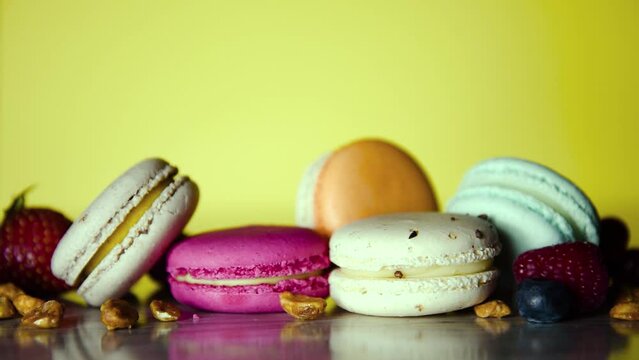 A girl's hand puts macarons in the frame, the photographer lays out a composition of French desserts and fruits on a blue photo.