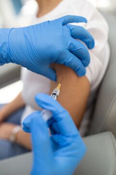 Close up of shot a healthcare worker with blue gloves giving a shot to a woman