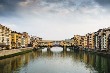 View of the Arno River in Italy and the historic Ponto Vecchio bridge with reflection in the water