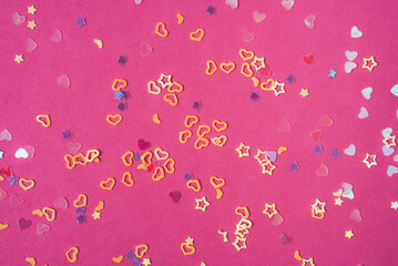 Multicolored sequins in the shape of a heart and a star on a pink background