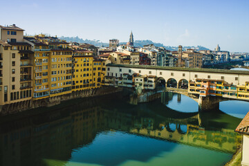 Naklejka premium View of the Arno River in Italy and the historic Ponto Vecchio bridge with reflection in the water