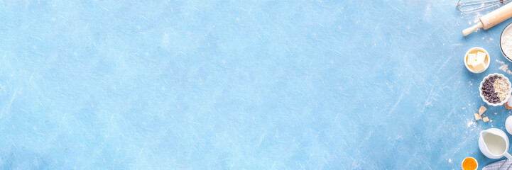 Baking ingredients background. Cooking ingredients (flour, eggs, milk, brown sugar, butter) with utensils on light blue background top view copy space