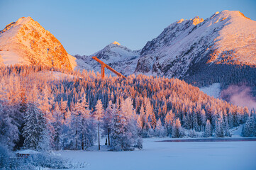 Frosty winter morning at Strbske Pleso under the High Tatras, with the first rays of sunlight illuminating the snow-covered landscape