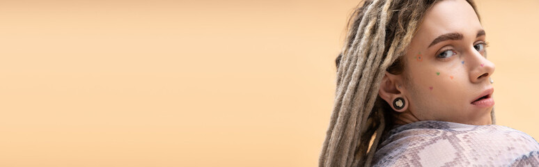 Young nonbinary person with dreadlocks looking at camera isolated on yellow, banner.